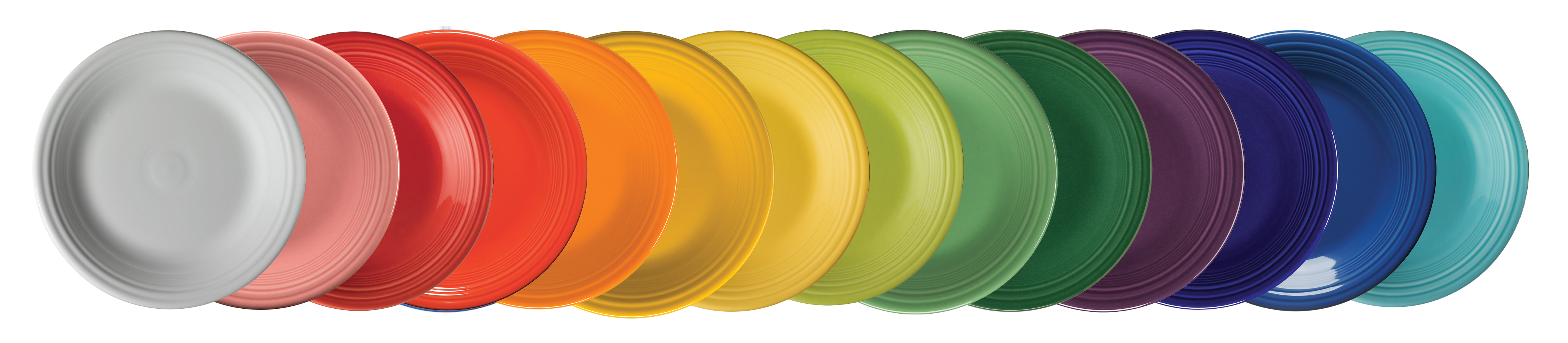 A long horizontal stack of Fiesta plates arranged as a rainbow, from reds through oranges, yellows, greens, blues and purples.